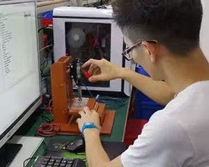 Person working on a computer with a monitor displaying text, in an indoor setting.